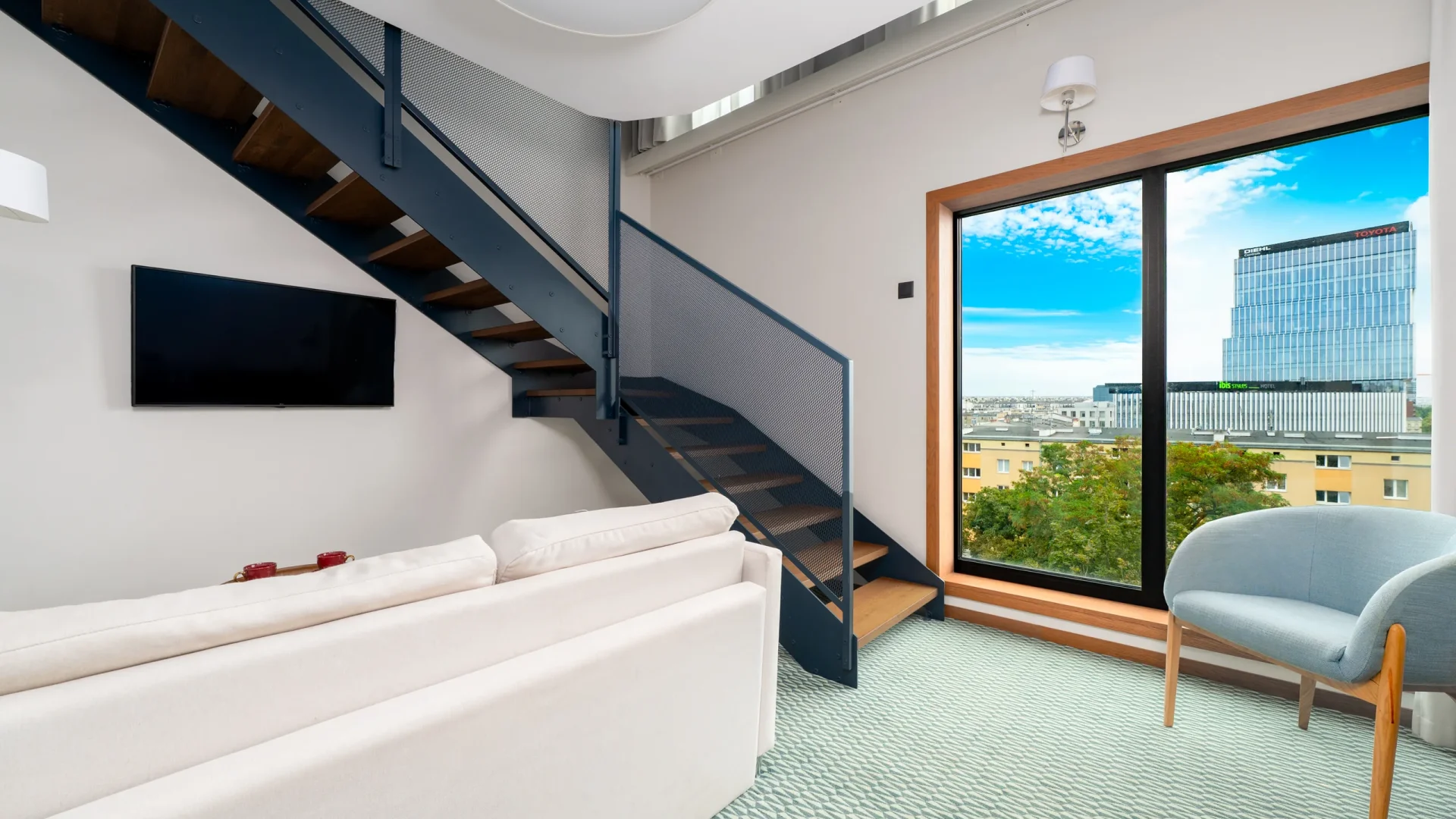 Duplex Deluxe - schody na antresolę i duże okno z widokiem na miasto