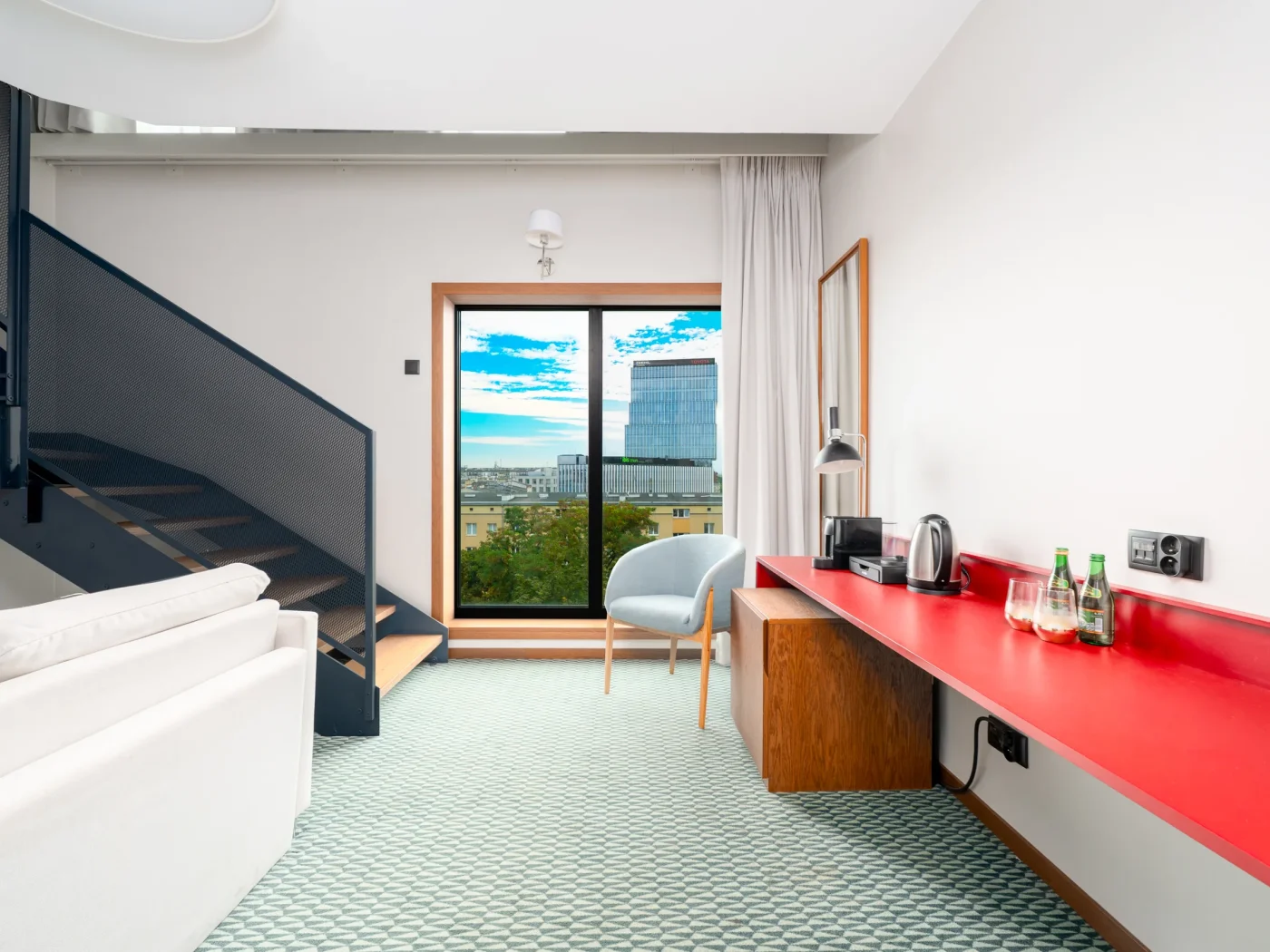 Dolny poziom apartamentu ze schodami i czerwonym biurkiem