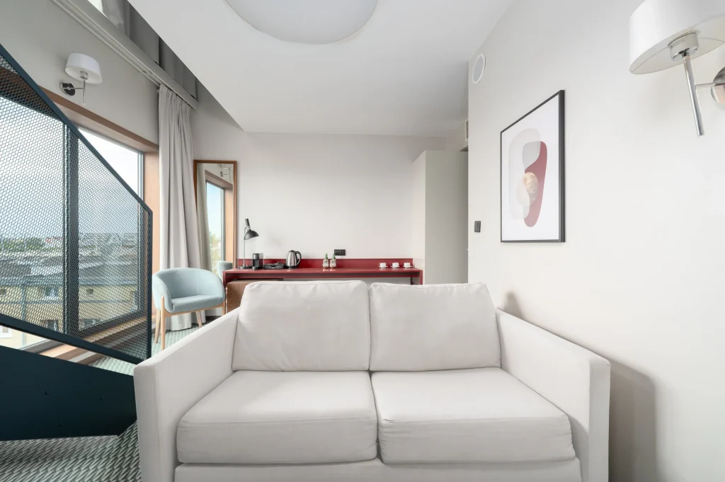 Sofa na dolnym poziomie apartamentu, w tle balkon