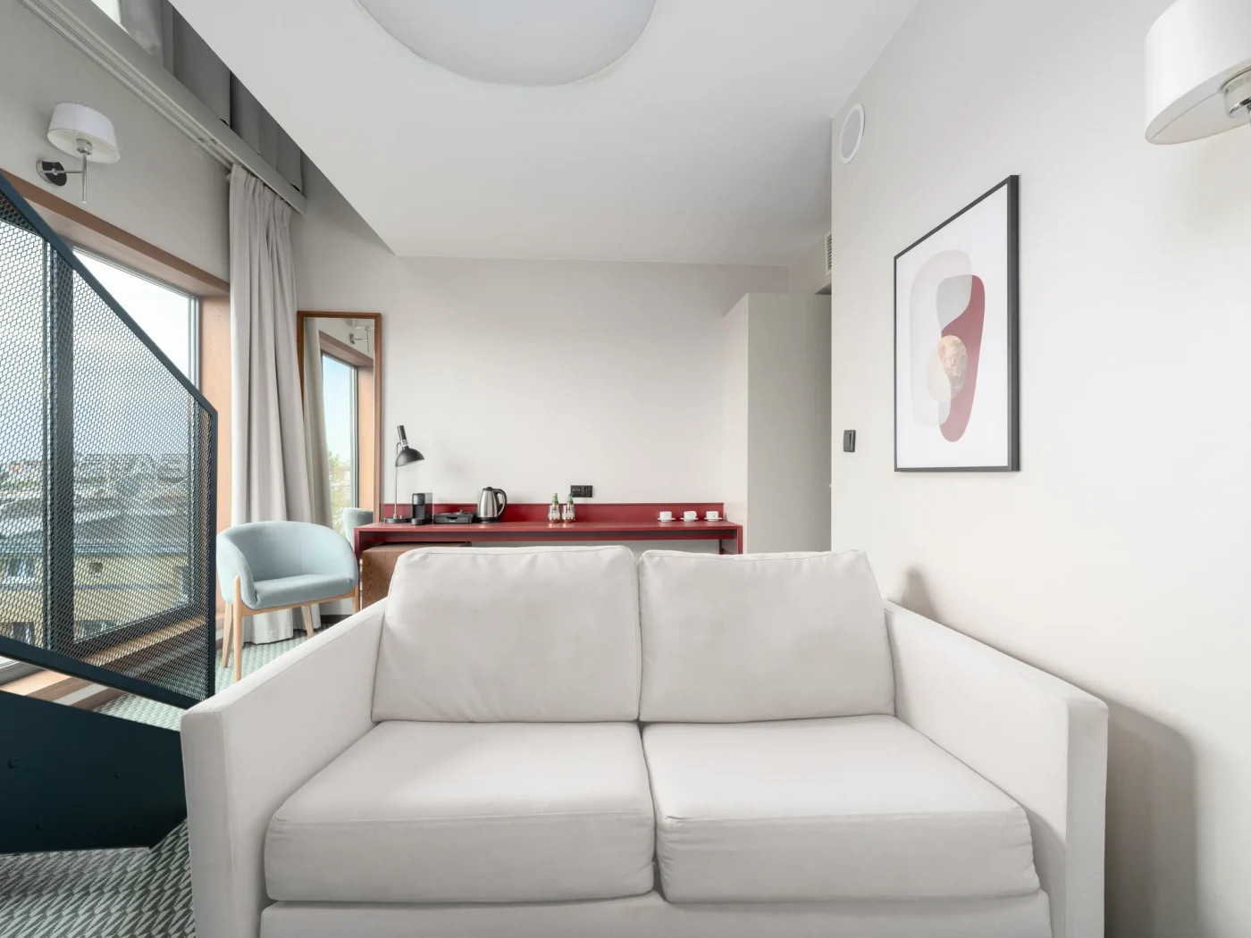 Sofa na dolnym poziomie apartamentu, w tle balkon