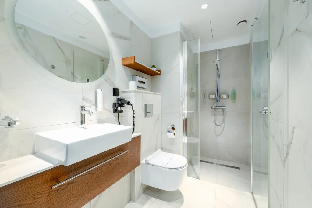 Bathroom with a washbasin, round mirror and shower enclosure