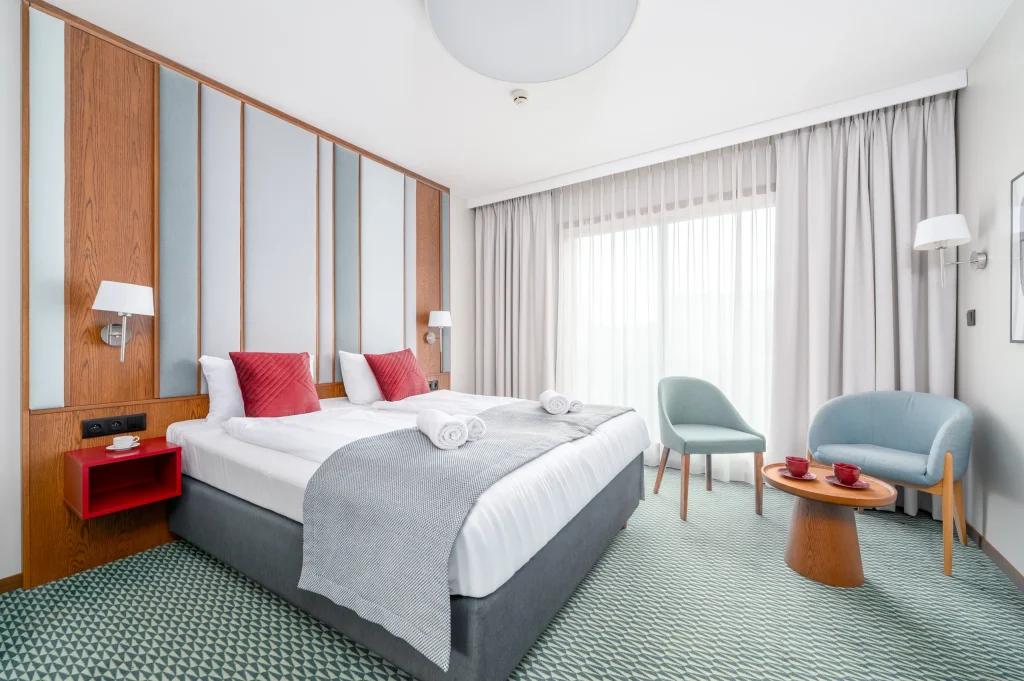 Superior Double room with a double bed, red cushions, armchairs and a red desk