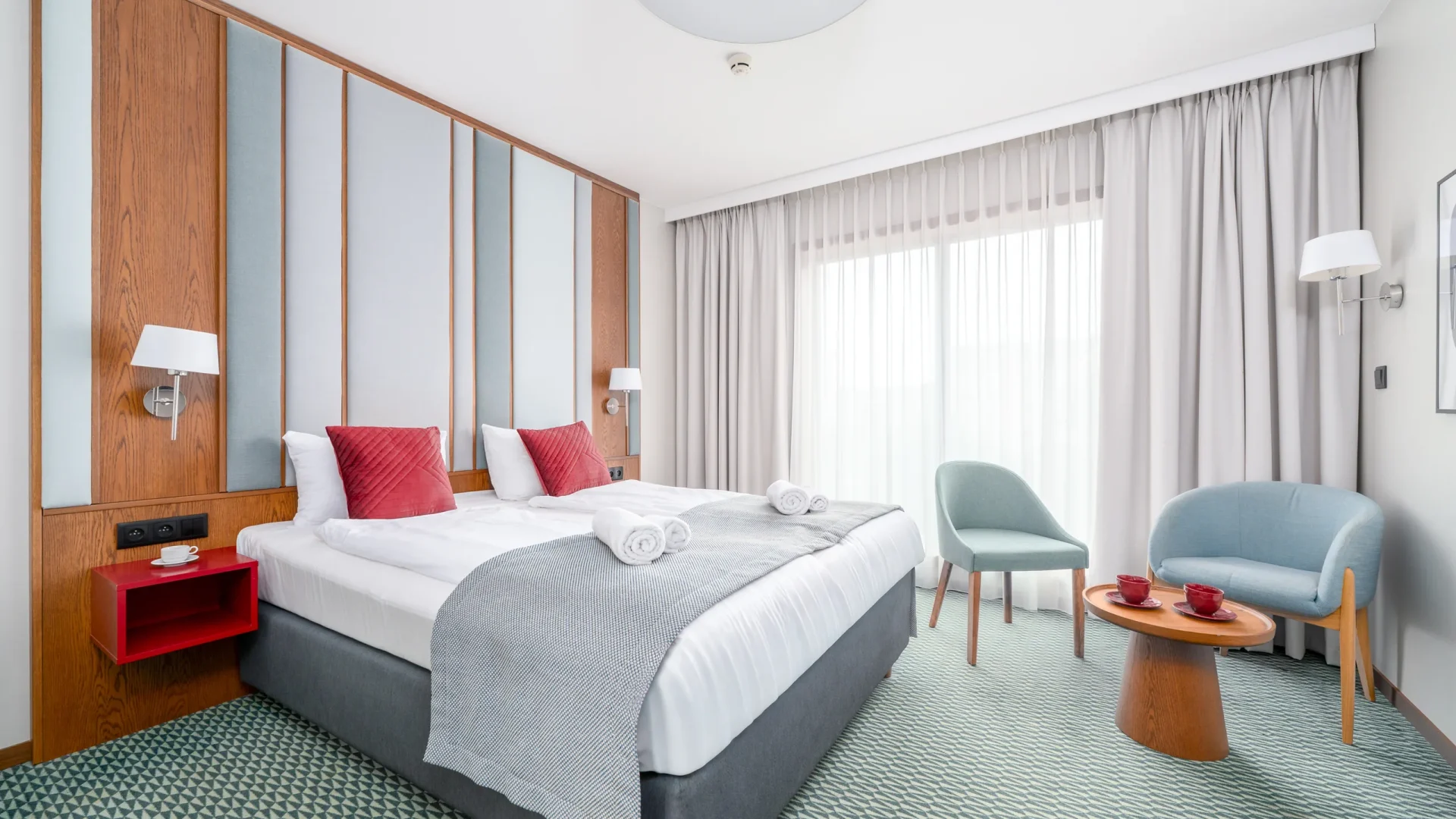 Superior Double room with a double bed, red cushions, armchairs and a red desk