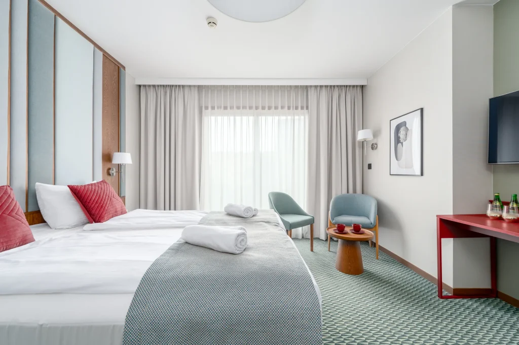 Double bed with a red desk and television in the background