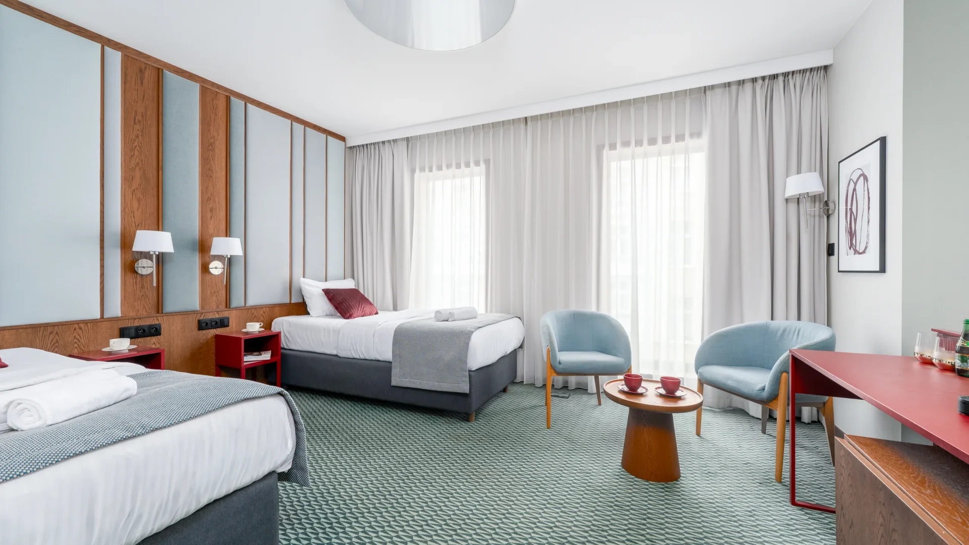 Two beds, armchairs and a window with a sheer curtain