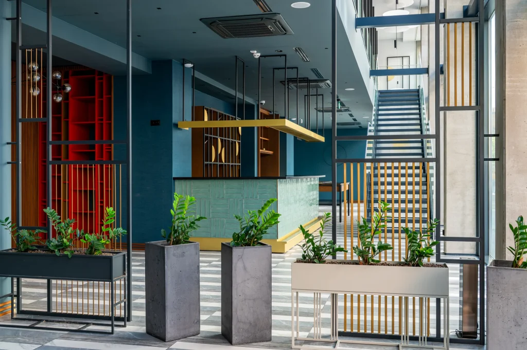 Lobby with plants, stairs and a red wall