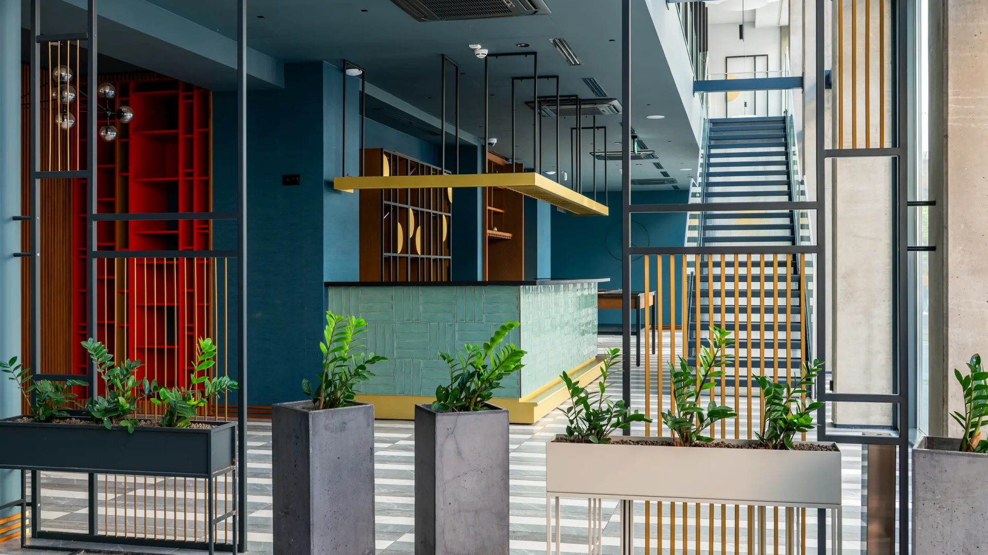 Lobby with plants, stairs and a red wall