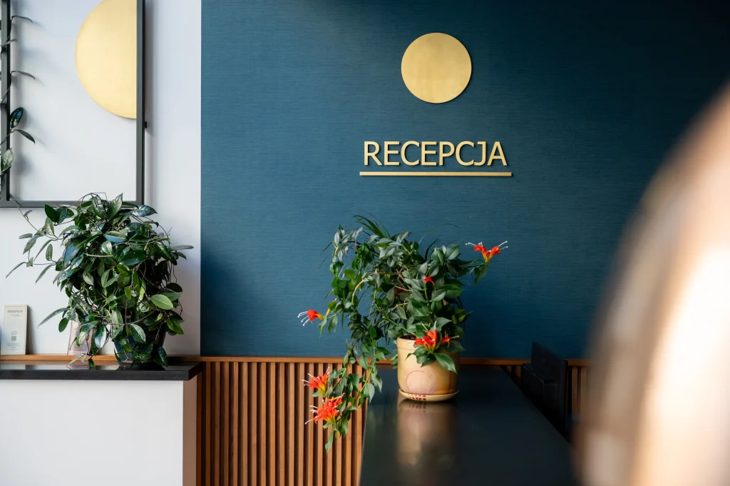 The word Recepcja and a gold circle on a navy-blue wall